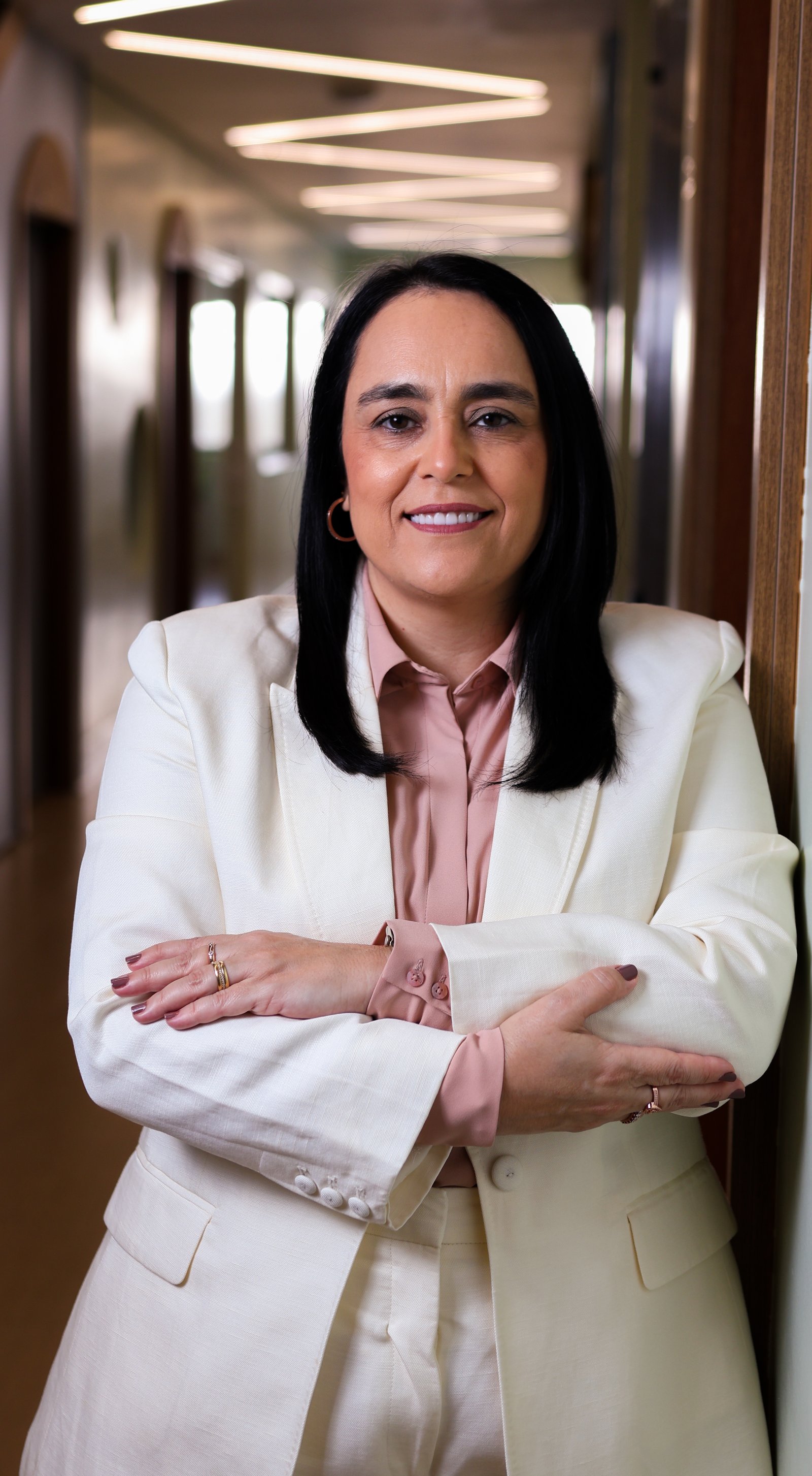 Patrícia Bastos em um corredor, de braços cruzados